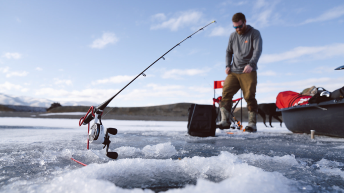A rod and a hole in the ice with a man at the back